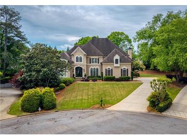 Stunning two-story home boasts a manicured lawn and a circular driveway at 2049 Kinderton Manor Dr, Johns Creek, GA 30097
