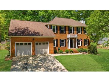 Traditional brick home featuring a two-car garage, manicured lawn, and charming architectural details at 2700 Sandstone Dr, Lawrenceville, GA 30043