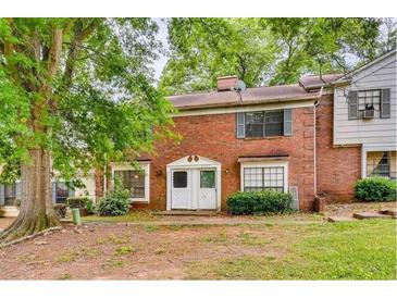 Traditional brick townhouse with a lush green lawn and mature trees at 6593 Sleepy Hollow Ln, Morrow, GA 30260
