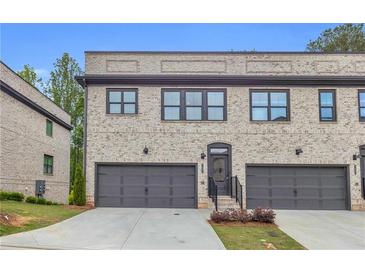 Charming townhome featuring a gray brick facade, a two-car garage, and a well-maintained lawn at 3493 Monarch Ave, Duluth, GA 30096