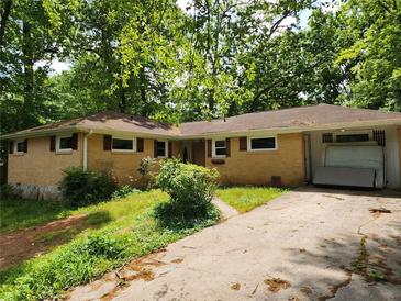 Charming single-story brick home featuring a covered parking area and surrounded by lush greenery and mature trees at 1321 Snapfinger Rd, Decatur, GA 30032