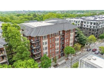 Charming brick condo building with a gray roof and multiple balconies surrounded by lush green trees at 850 Piedmont Ne Ave # 1409, Atlanta, GA 30308