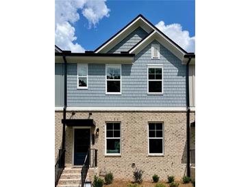 Charming two-story townhome with a brick and shingle exterior, complemented by well-manicured landscaping at 1242 Ainsworth Aly # 40, Sugar Hill, GA 30518