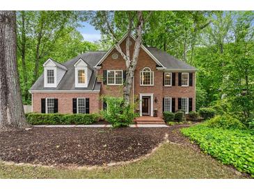 Charming two-story brick home with dormer windows, black shutters, and mature trees on a lush landscaped lot at 4442 Freeman Rd, Marietta, GA 30062