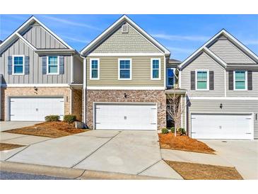 Charming townhouse with brick accents, white garage door, and well-maintained landscaping on a sunny day at 7492 Knoll Hollow Rd, Lithonia, GA 30058