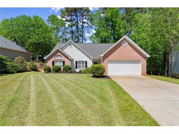 Charming single-story home featuring a brick facade, two-car garage, and a well-manicured lawn with mature trees at 2880 Cressington Nw Bnd, Kennesaw, GA 30144