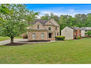 Charming brick home featuring a well-manicured lawn and mature trees in a serene, suburban setting at 2480 Ashbourne Dr, Lawrenceville, GA 30043