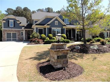 Charming two-story home with a manicured lawn, detailed trim, and a stone address marker at 4960 Shade Creek Xing, Cumming, GA 30028