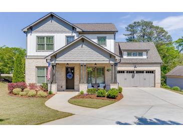 Charming two-story home with a brick and siding exterior, complemented by a well-manicured lawn and inviting front porch at 500 S Hill St, Buford, GA 30518