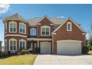 Elegant brick home showcasing a well-manicured lawn, mature landscaping, and a spacious three-car garage at 4240 Hastings Dr, Cumming, GA 30041