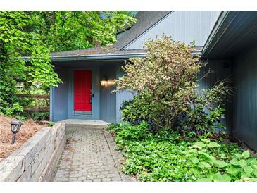 Charming home featuring a vibrant red front door, complemented by stone walkway and landscaped surroundings at 3863 Dundee Ne Dr, Roswell, GA 30075
