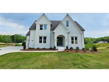 Beautiful two-story home showcasing white siding, dark roof, and manicured lawn at 6490 Mockingbird Rd, Cumming, GA 30028