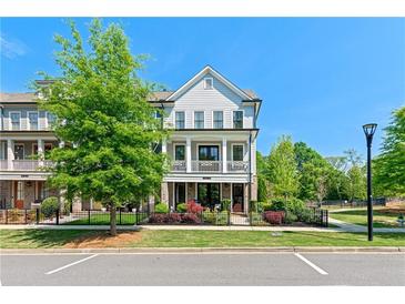 Charming townhome featuring a two-story facade with a covered porch and beautifully landscaped front yard at 130 Inwood Walk, Woodstock, GA 30188