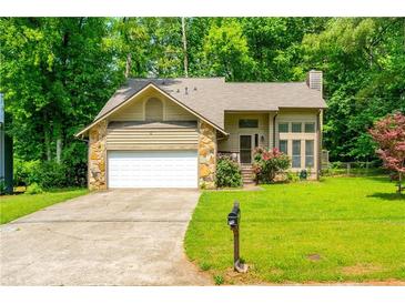 Charming single-Gathering home with a stone and siding exterior, green lawn, and mature trees at 1131 Bailing Dr, Lawrenceville, GA 30043