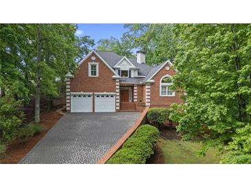 Charming two-story brick home with a well-manicured lawn and a two-car garage on a sunny day at 7830 Kings Point Dr, Cumming, GA 30041