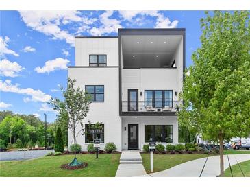 Modern two-story home featuring white brick, black trim, a covered balcony and a well-manicured lawn at 326 Treble Way, Alpharetta, GA 30009