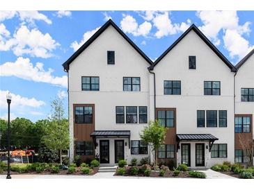 Modern townhome exterior featuring black-framed windows, a painted brick facade, and well manicured landscaping at 654 Soul Aly # 102, Alpharetta, GA 30009