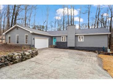 Charming single-story home with a gray exterior, blue door, stone accents and a large driveway at 1925 Commonwealth Ct, Cumming, GA 30041