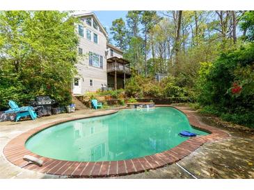 Backyard pool with a red-brick border offers a private, relaxing outdoor space with ample lounge seating at 225 Nacoochee Dr, Woodstock, GA 30188