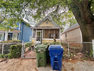 Charming yellow cottage with a screened porch, surrounded by lush trees and a fenced yard at 712 Garibaldi Sw St, Atlanta, GA 30310