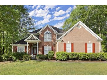 Charming two-story brick home with manicured lawn, lush landscaping, and a welcoming front entrance at 4635 Rutledge Dr, Snellville, GA 30039
