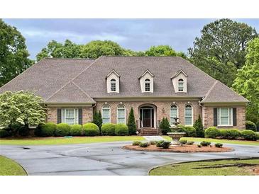 Elegant brick home featuring manicured landscaping, a circular driveway, and a charming water fountain at 1551 Pharrs Rd., Snellville, GA 30078