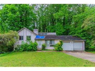 Two-story home with a two-car garage and a lawn surrounded by large trees at 1060 S Millard Way, Stone Mountain, GA 30088