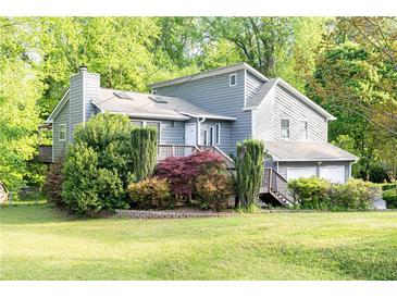 Charming gray home with lush landscaping and a welcoming front porch surrounded by mature trees at 4065 Maxanne Nw Dr, Kennesaw, GA 30144