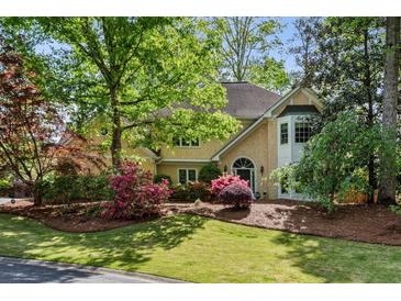 Charming two-story home featuring a well-manicured lawn with mature trees and beautiful, colorful landscaping at 1824 Mallard Lake Dr, Marietta, GA 30068