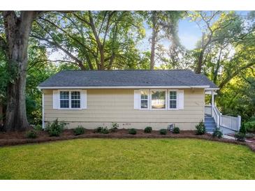 Charming single-story home with light yellow siding, white-framed windows, and well-manicured landscaping at 1900 Meadow Ln, Decatur, GA 30032