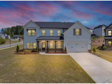 Charming two-story home features a welcoming front porch, well-manicured lawn, and an attached two-car garage at 4890 Revere Way, Cumming, GA 30028