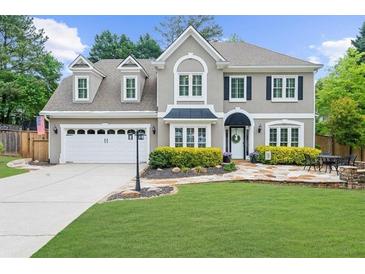 Charming two-story home featuring manicured lawn, a two-car garage, and a welcoming stone pathway to the front door at 230 Bristolstone Ct, Alpharetta, GA 30005