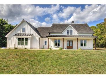 Charming two-story farmhouse featuring white siding, a cozy porch swing, and a well-manicured front lawn at 613 Nebo Rd, Dallas, GA 30157