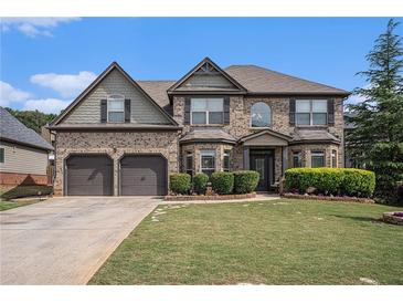 Beautiful two-story brick home with a well-manicured lawn and a three-car garage under a blue sky at 812 Nevis Way, Mcdonough, GA 30253