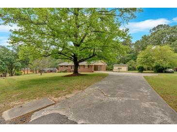 Charming brick home featuring a spacious front yard with a large, mature tree and a long driveway at 115 Pine Tree Dr, Fayetteville, GA 30214