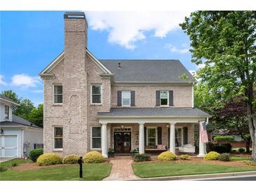 Charming brick two-story home with a covered front porch, columns, and a professionally landscaped yard at 215 Scott Xing, Roswell, GA 30076