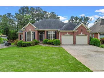 Brick home with a well-manicured lawn, two-car garage, and mature landscaping at 5510 Conway Dr, Marietta, GA 30068