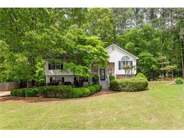 Charming home featuring lush landscaping, stone accents, and a well-manicured lawn, all nestled amongst mature trees at 174 Cannon Pl, Dallas, GA 30157