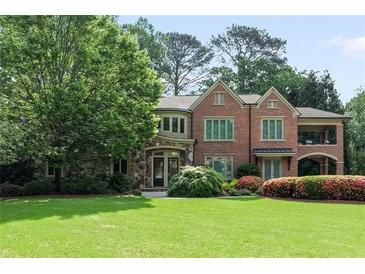 Charming brick home with stone accents, arched porch, lush landscaping, and mature trees on a well-manicured lawn at 4835 Merlendale Ct, Atlanta, GA 30327