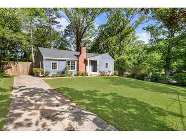 Charming blue home with a brick chimney and a spacious front yard surrounded by lush trees and a concrete driveway at 1541 Pontiac Se Pl, Atlanta, GA 30315