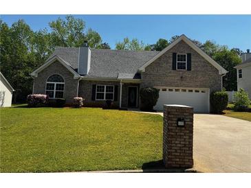 Charming brick home with a well-manicured lawn, driveway, and colorful flowerbeds at 20 Chapman Way, Covington, GA 30016