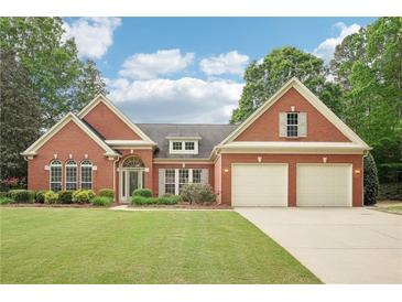 Charming brick home featuring a well-manicured lawn, mature trees, and a two-car garage at 1675 Bookhout Dr, Cumming, GA 30041