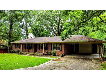 Ranch-style brick home featuring a covered carport and a lush, tree-filled front yard at 6470 Sherwood Trl, Austell, GA 30168