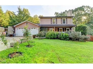 Charming two-story home featuring a well-manicured lawn, mature landscaping, and an attached two-car garage at 4364 Saddlecreek Ct, Auburn, GA 30011