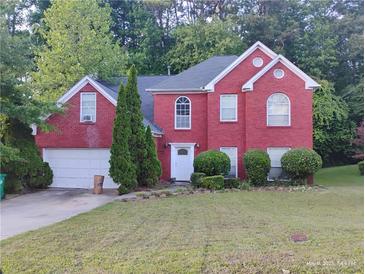 Charming two-story red brick home with a well-manicured lawn and attached two car garage at 5206 Panola Mill Dr, Lithonia, GA 30038