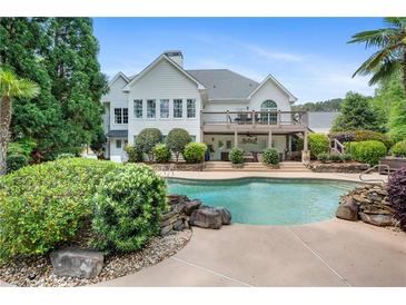 Tranquil backyard with a sparkling pool, mature landscaping, a deck, and a stone retaining wall at 109 Hawks Bnd, Canton, GA 30115