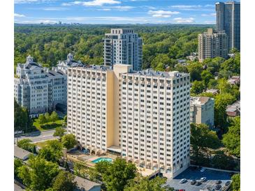 Stunning view of the high-rise condo building showing the pool, parking, and mature trees at 2479 Peachtree Ne St # 1414, Atlanta, GA 30305