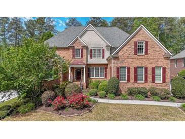 Charming brick home featuring a meticulously landscaped front yard and mature trees at 2439 Huntington Park Nw Dr, Acworth, GA 30101