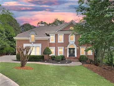 Stunning two-story brick home with manicured lawn, mature trees, and classic architectural details at 515 Old Chartwell Xing, Alpharetta, GA 30022