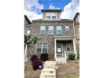 Charming brick townhome with a covered front porch and well-manicured landscaping, and concrete stairs at 3658 Hidden Valley Cir, Lawrenceville, GA 30044
